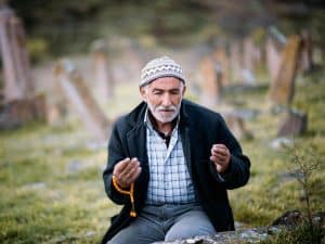 muslim man making dua while at graveyard