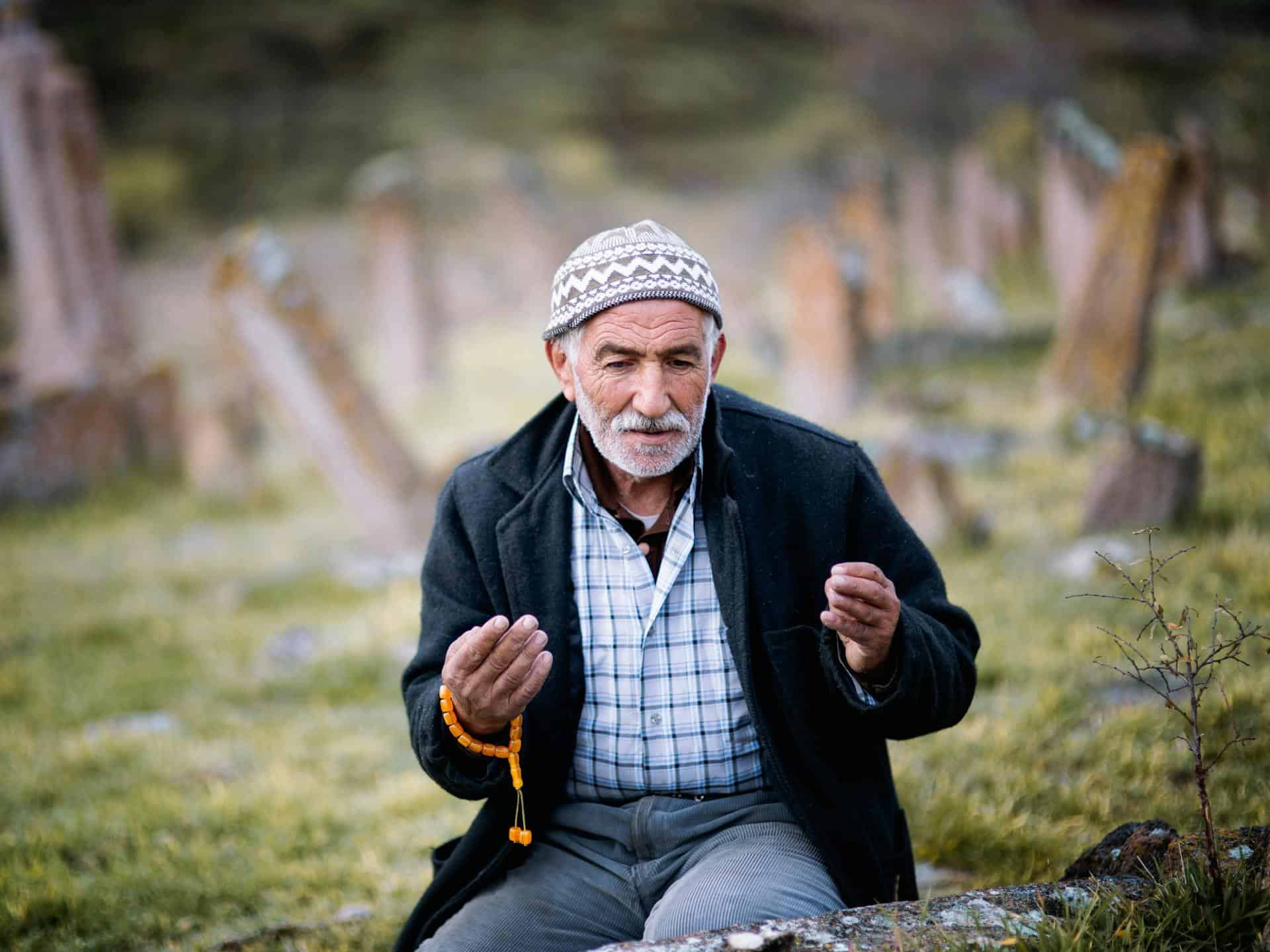 muslim man making dua while at graveyard